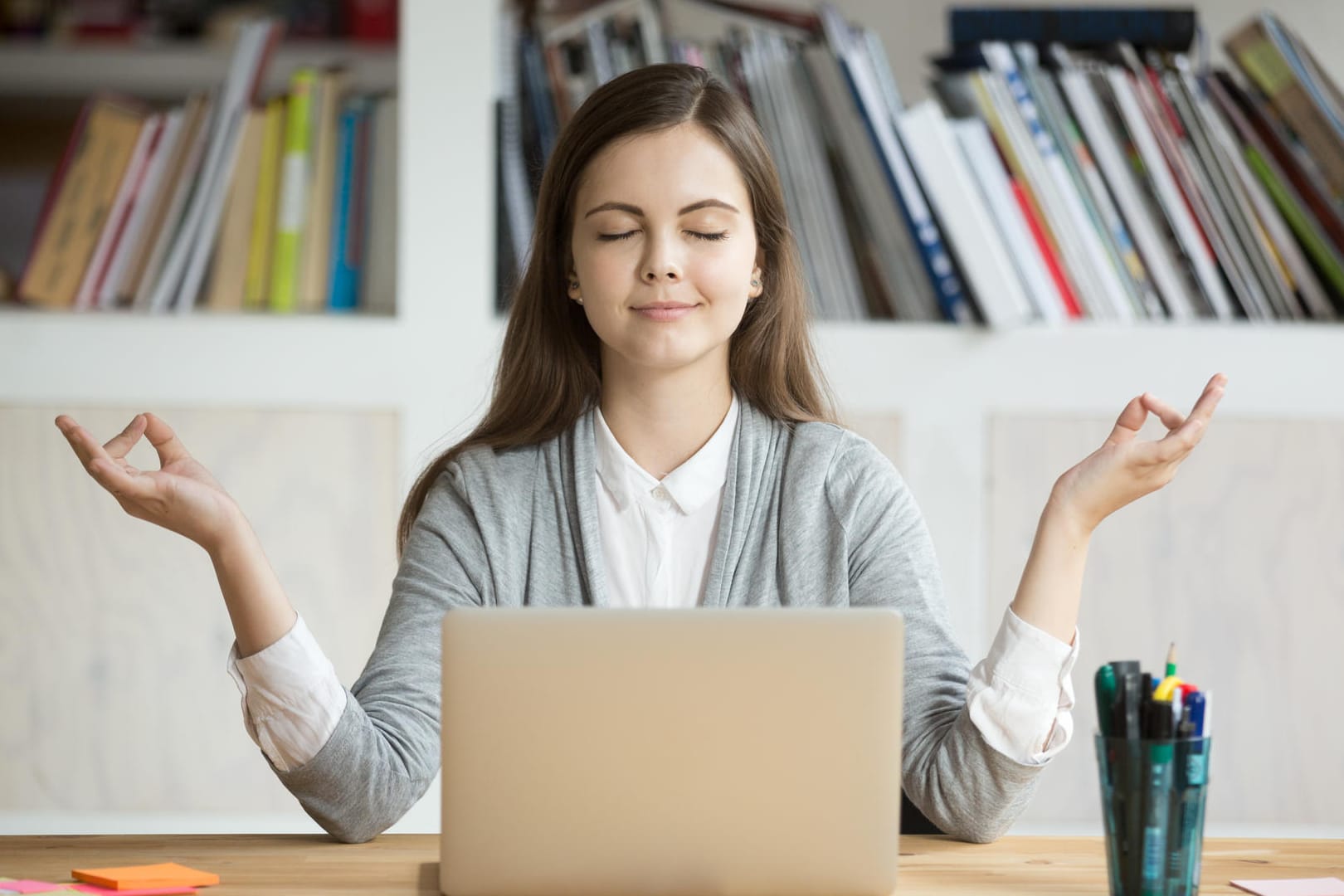 Frau meditiert vor einem Computer: Die Balance zwischen Arbeit und Freizeit zu finden, ist nicht immer leicht.