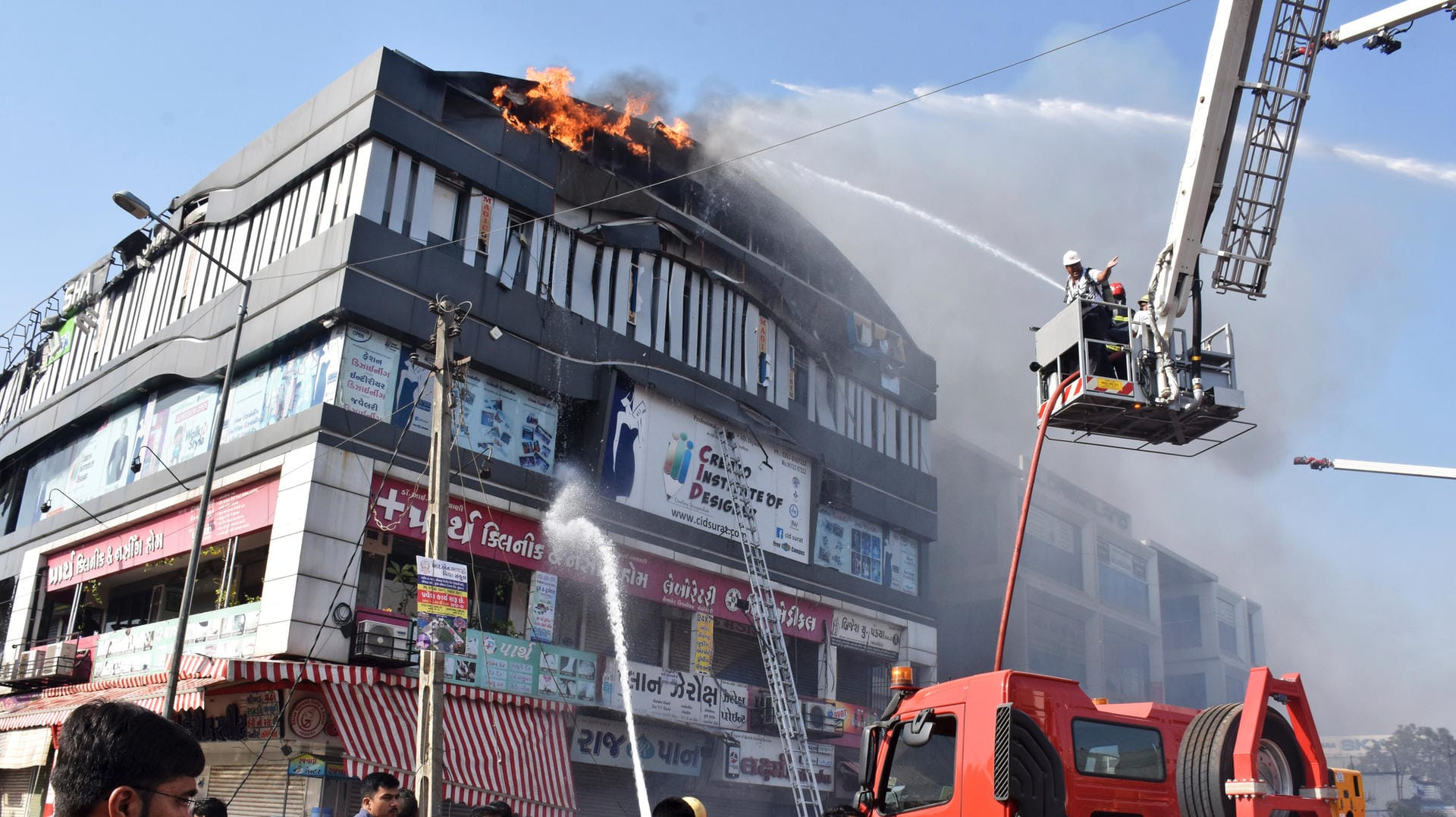 Surat in Indien: Feuerwehrleute löschen Flammen, die aus einem Gebäude lodern. Zahlreiche Jugendliche kamen bei dem Brand ums Leben. Surat in Indien: Feuerwehrleute löschen Flammen, die aus einem Gebäude lodern. Zahlreiche Jugendliche kamen bei dem Brand ums Leben.