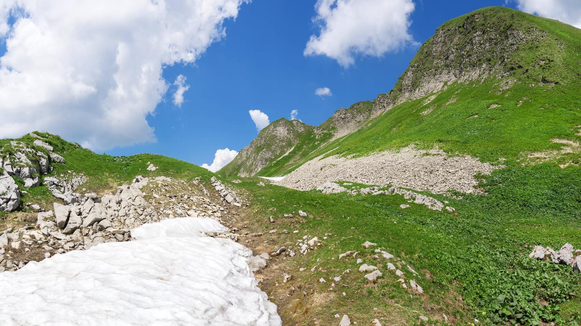 Schneereste am grünen Berg im Allgäu (Symbolbild): Ein Mann hat sich bei einem Sturz in Bayern schwer verletzt.