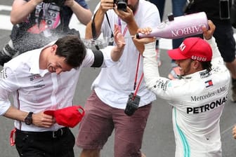 Lewis Hamilton (r) duscht Mercedes-Teamchef Toto Wolff mit Champagner.