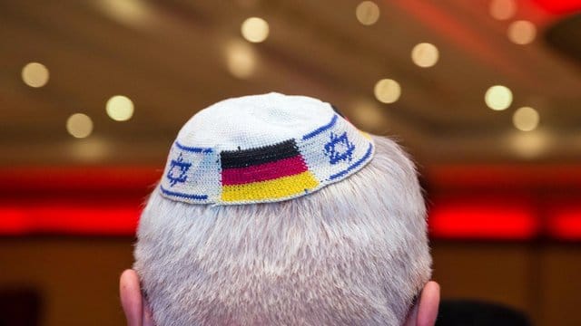 Ein Mann trägt eine Kippa mit eingearbeiteten israelischen und deutschen Fahnen.