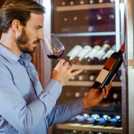 Mann verkostet Rotwein: Ein Weinkühlschrank sorgt dafür, dass Ihre Sammlung stets optimal temperiert gelagert wird.