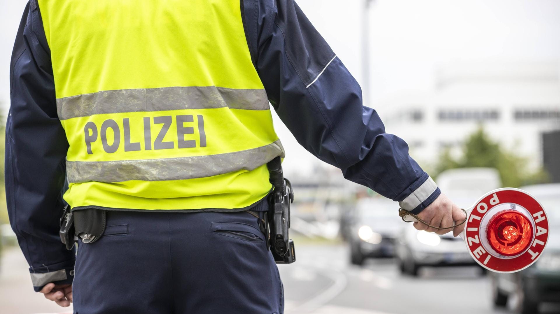 Polizist mit gelber Warnweste und Anhaltekelle bei einer Verkehrskontrolle. Polizist mit gelber Warnweste und Anhaltekelle bei einer Verkehrskontrolle.