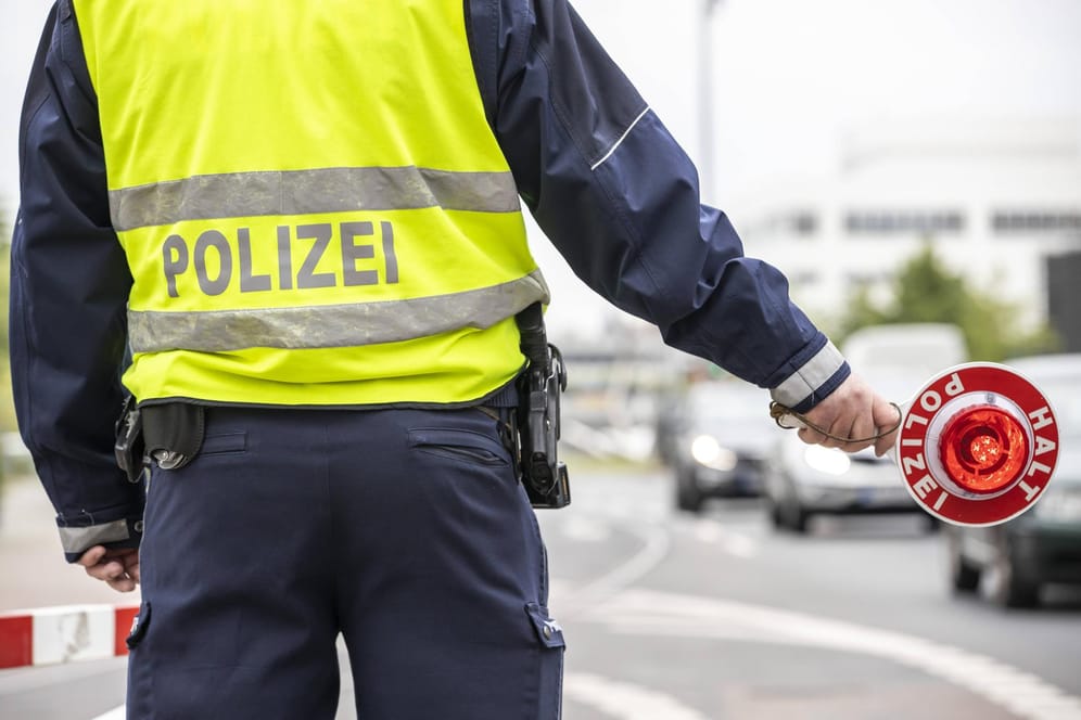 Polizist mit gelber Warnweste und Anhaltekelle bei einer Verkehrskontrolle.