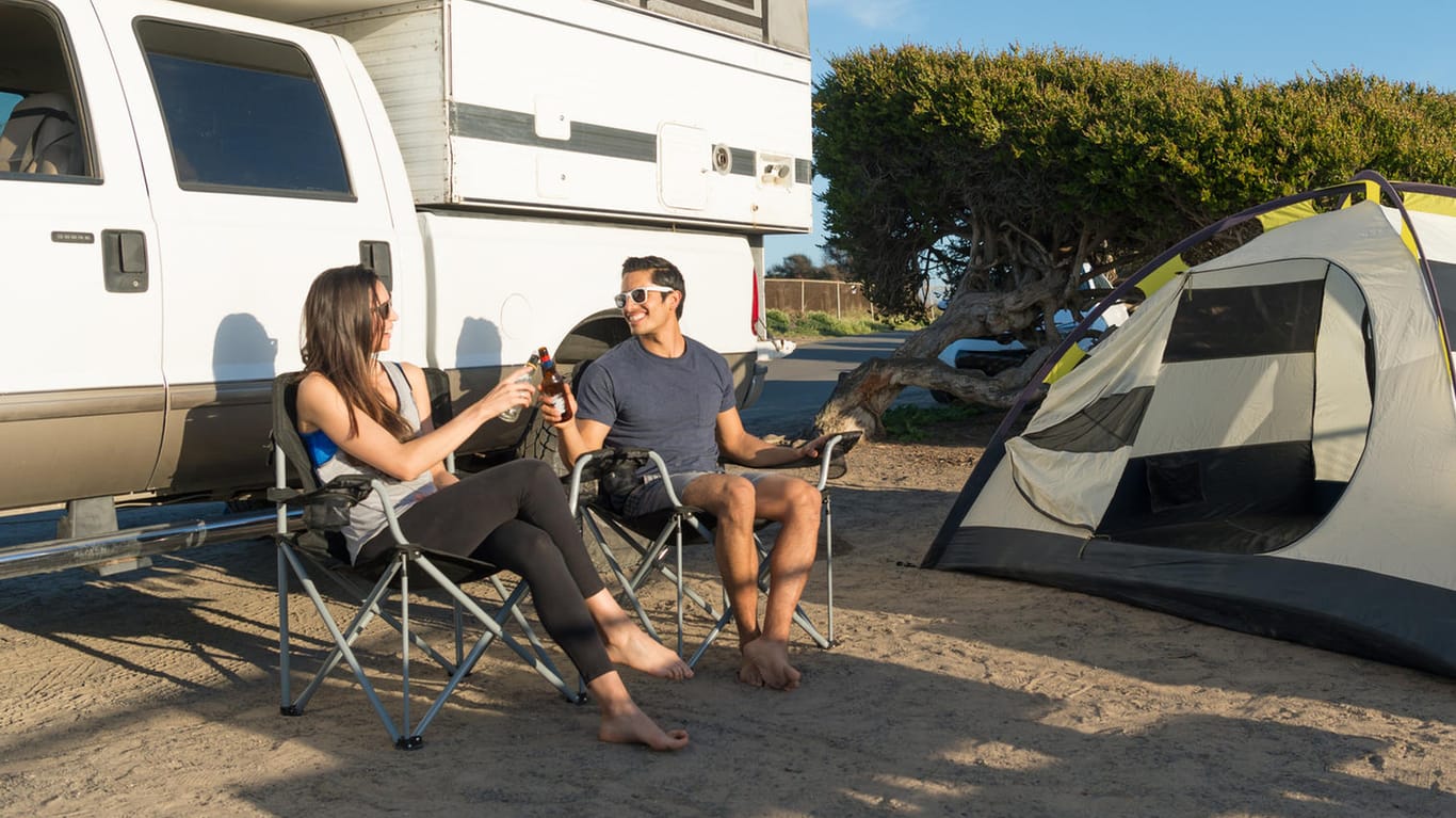 Paar beim Camping: Damit es zu keinem bösen Erwachen im Urlaub kommt, sollte der Versicherungsschutz gecheckt werden.