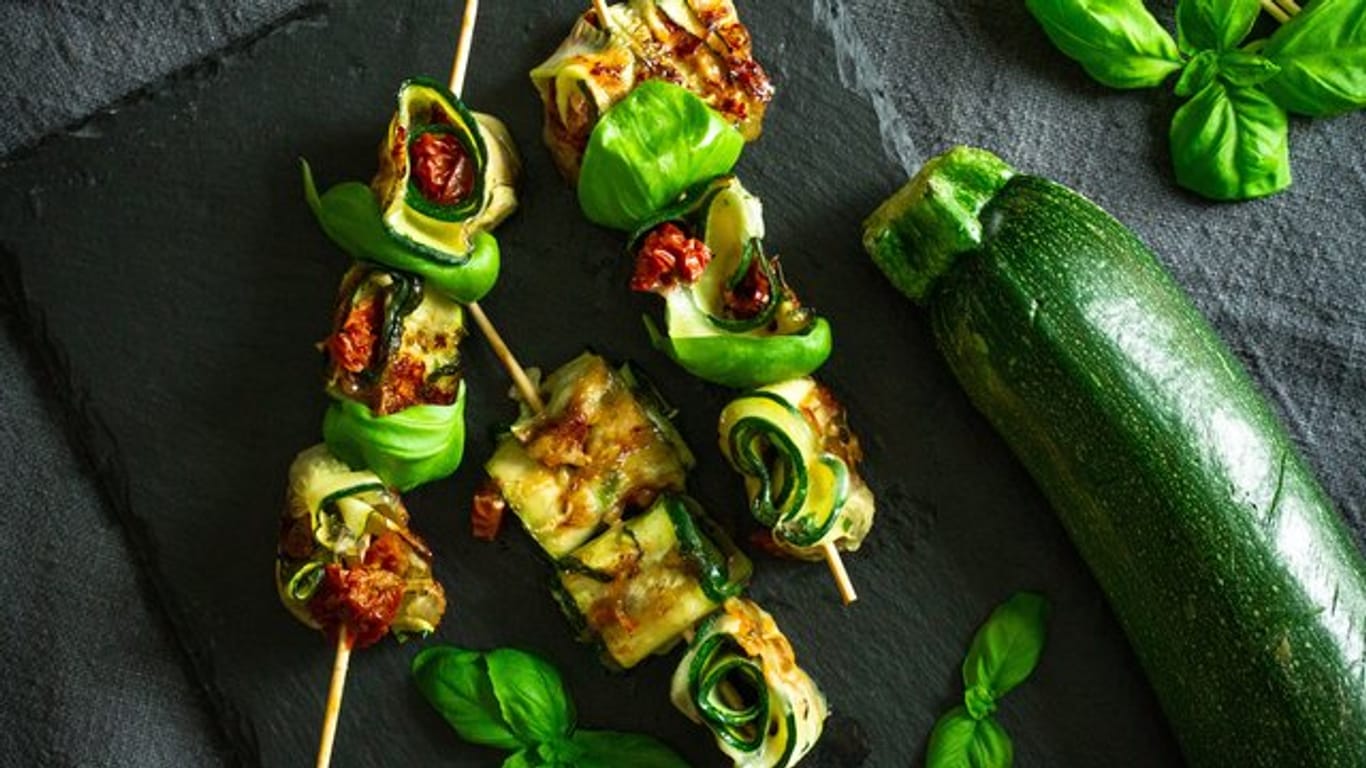 Die Zucchinischeiben werden mit Mozarella und getrockneten Tomaten belegt, dann aufgerollt und schließlich auf Holzspießchen fixiert.