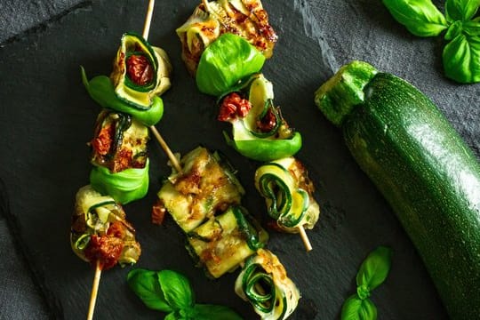 Die Zucchinischeiben werden mit Mozarella und getrockneten Tomaten belegt, dann aufgerollt und schließlich auf Holzspießchen fixiert.