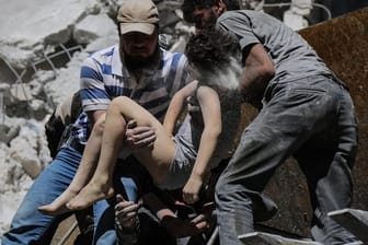Mitglieder der syrischen Weißhelme und Freiwillige retten ein verletztes Kind aus den Trümmern eines Gebäudes, das bei einem Luftangriff durch die syrischen Regierungskräfte beschädigt wurde.