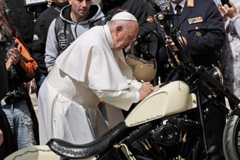 Papst Franziskus unterschreibt auf einer Harley-Davidson, während er Mitglieder der Gruppe "Jesus Bikers International" auf dem Petersplatz trifft.