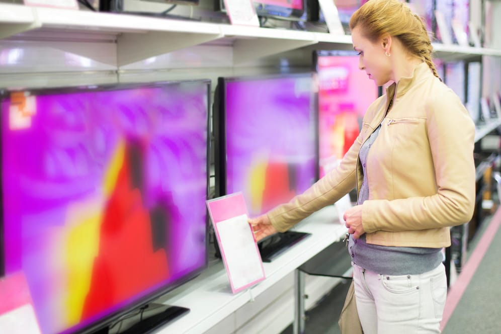 Eine Frau sieht sich neue Fernseher in einem Elektronikmarkt an: UHD, OLED, HDR und so weiter – die Abkürzungen auf dem TV-Markt können verwirrend sein.
