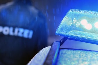 Ein Polizist vor einem Streifenwagen (Symbolbild): In Sachsen hat ein 13-Jähriger mit einem gestohlenen Auto einen Unfall gebaut.