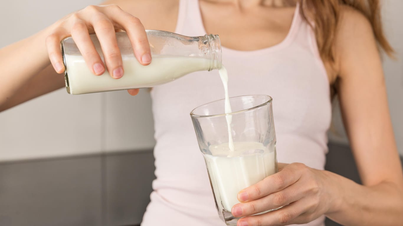 Frau gießt Milch in ein Glas: Ist Milch wirklich schädlich für die Gesundheit?