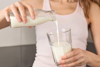 Frau gießt Milch in ein Glas: Ist Milch wirklich schädlich für die Gesundheit?