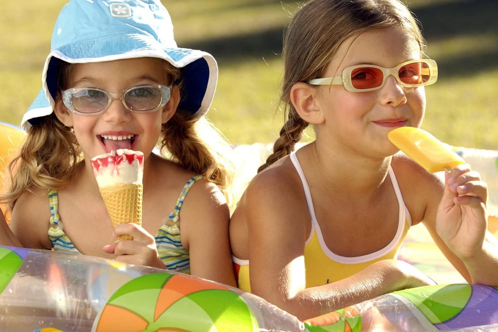 Zwei Mädchen essen Eis: Es wird heiß – da wird wohl auch das ein oder andere Eis drin sein.