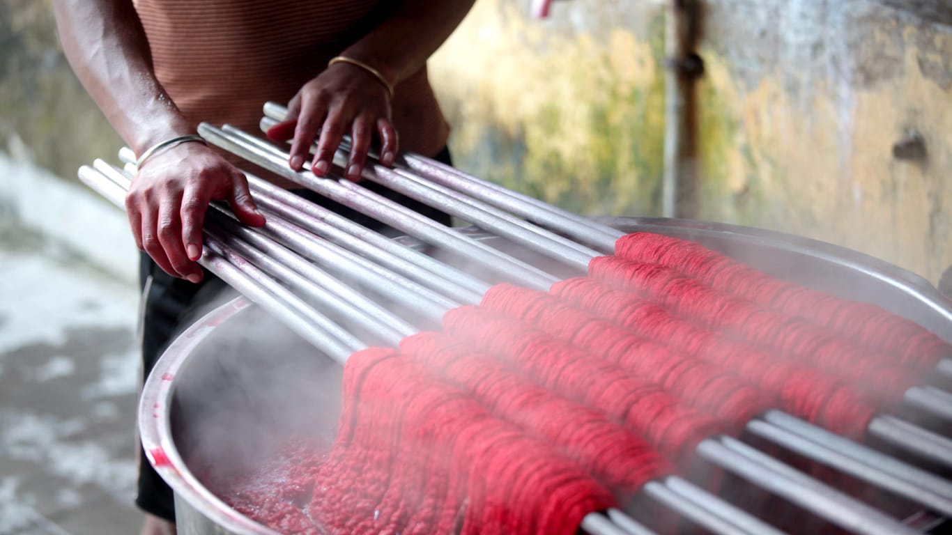 Ein Arbeiter färbt Baumwollgarn: Der Baumwollanbau in Indien bringt mehrere Probleme mit sich.