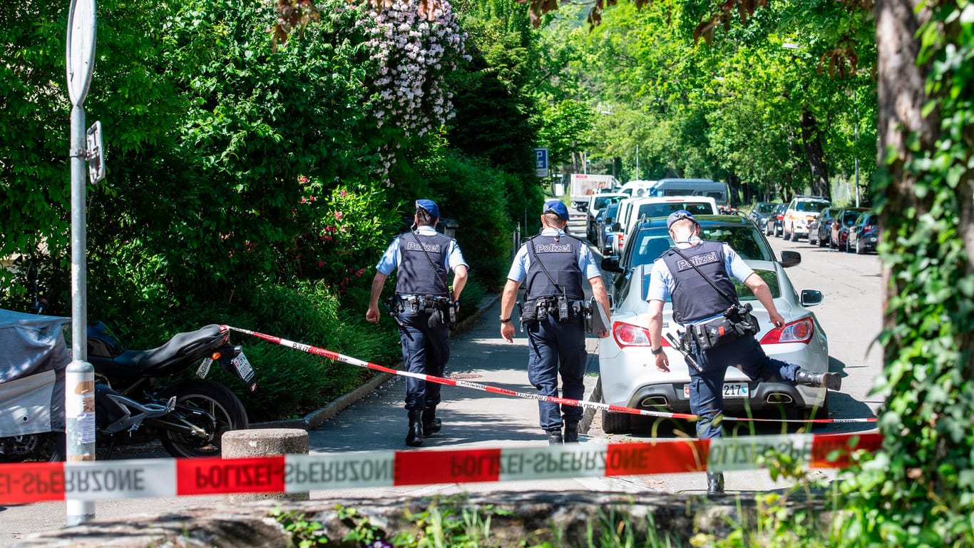 Zürich: Einsatzkräfte der Polizei gehen hinter einer Absperrung. In einem Wohnhaus hat es eine Geiselnahme mit Toten gegeben.