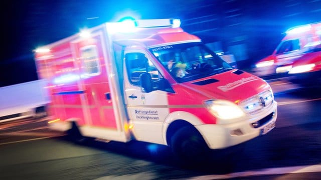 Ein Rettungswagen der Feuerwehr fährt mit Blaulicht durch eine Straße.