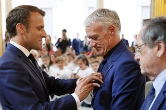 Frankreichs Präsident Emmanuel Macron (l) verleiht die Medaille der Ehrenlegion an Trainer Didier Deschamps.