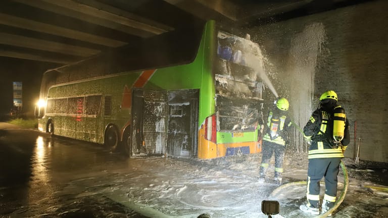 Feuerwehrleute löschen einen Reisebus: In dem Bus ist auf der Autobahn 1 bei Bremen ein Feuer ausgebrochen.