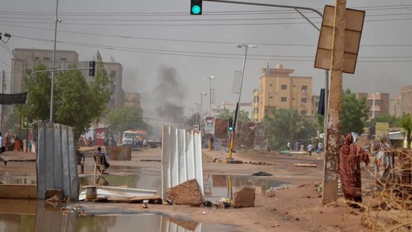 Rauch steigt in Khartum hinter einer Straßenbarrikade auf, die Militärfahrzeuge am Durchkommen hindern soll.