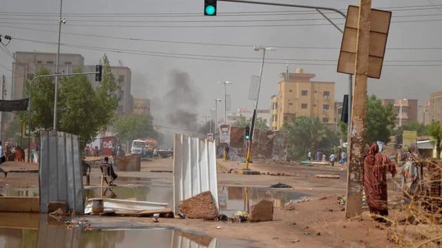 Rauch steigt in Khartum hinter einer Straßenbarrikade auf, die Militärfahrzeuge am Durchkommen hindern soll. Rauch steigt in Khartum hinter einer Straßenbarrikade auf, die Militärfahrzeuge am Durchkommen hindern soll.