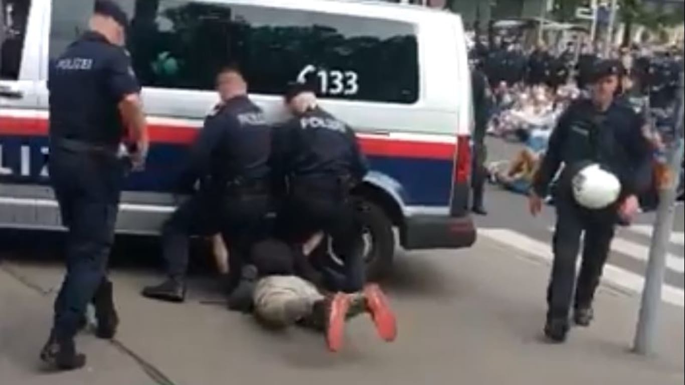 Demonstrant unter einem Einsatzwagen der Polizei: Am Rande einer Klimademo in Wien kam es zu lebensgefährlichen Szenen.