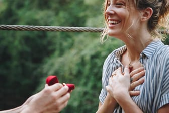 Frau hält sich gerührt die Hände vor die Brust: Ein Hochzeitsantrag kann ein sehr emotionaler Moment sein.