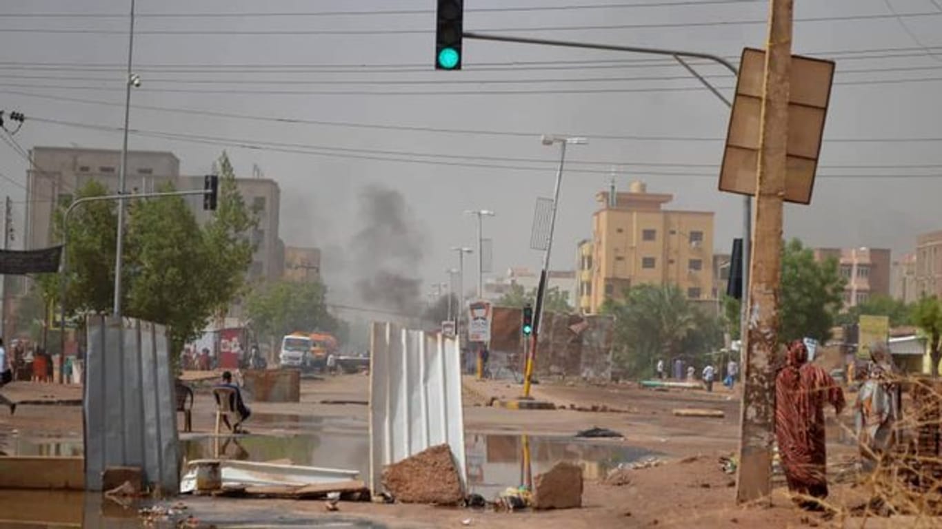 Rauch steigt in Khartum hinter einer Straßenbarrikade auf, die Militärfahrzeuge aufhalten soll.