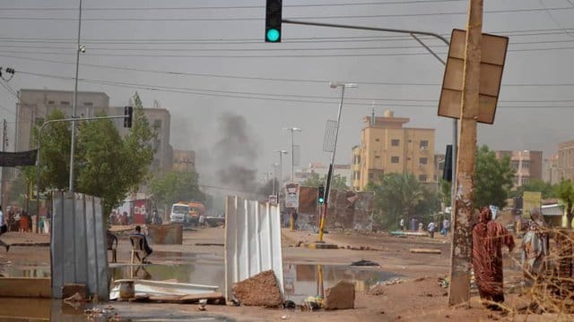 Rauch steigt in Khartum hinter einer Straßenbarrikade auf, die Militärfahrzeuge aufhalten soll. Rauch steigt in Khartum hinter einer Straßenbarrikade auf, die Militärfahrzeuge aufhalten soll.