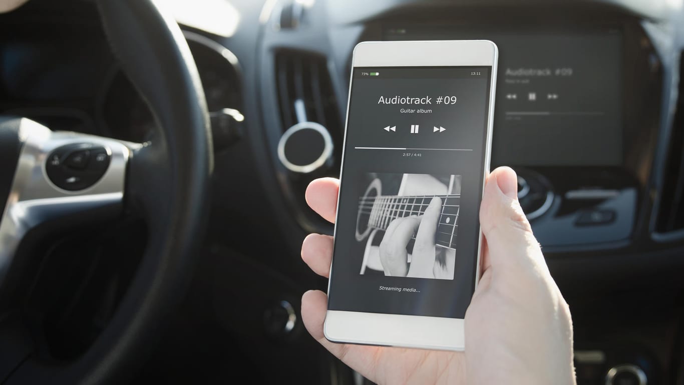 Ein Smartphone im Auto: Mit einem FM-Transmitter übertragen Sie Musik zum Autoradio.