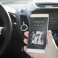Ein Smartphone im Auto: Mit einem FM-Transmitter übertragen Sie Musik zum Autoradio.