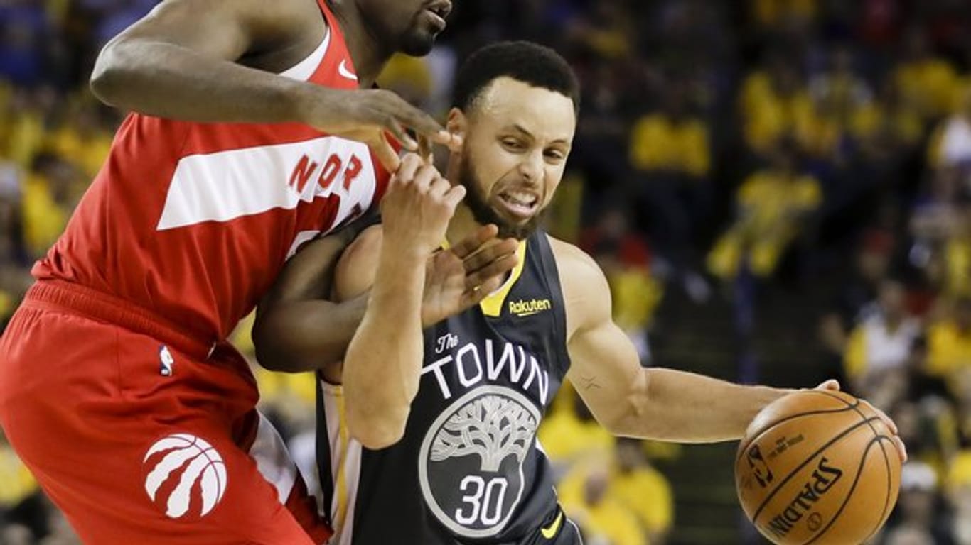 Stephen Curry (r) von den Golden State Warriors behauptet sich gegen Serge Ibaka von den Toronto Raptors.