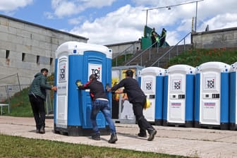 Arbeiter schieben ein Dixiklo aufs Gelände von Rock im Park