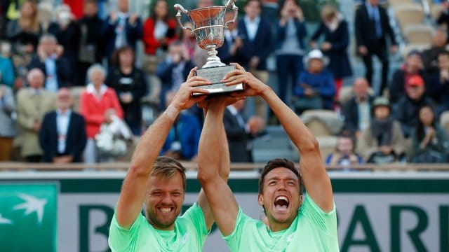 Kevin Krawietz (l) und Andreas Mies jubeln nach dem Turniersieg mit dem Pokal.