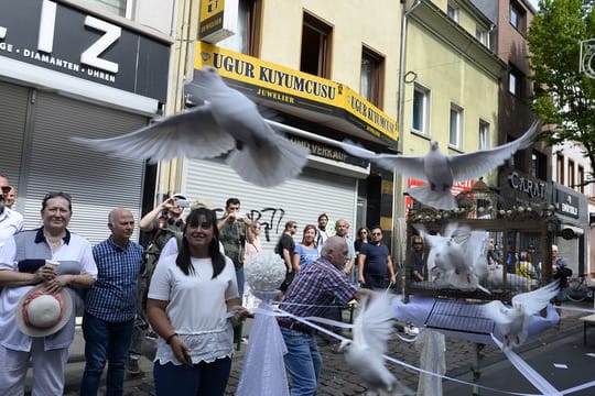 Teilnehmer einer Schweigeminute lassen auf der Kölner Keupstrasse am 15.