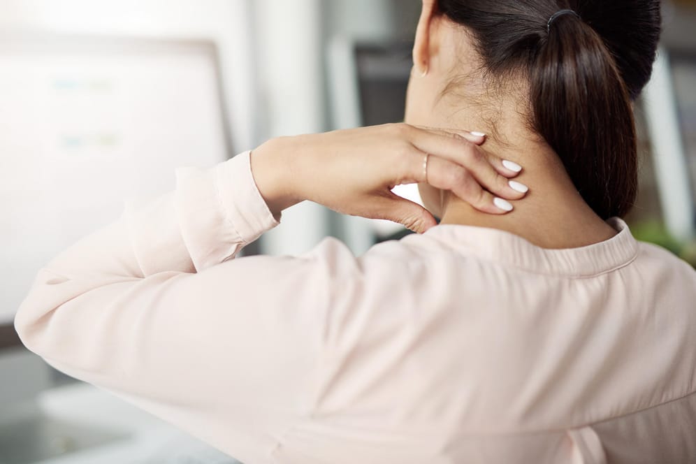 Frau hat Nackenschmerzen: Fehlhaltungen am Arbeitsplatz bekommt man schnell im Nacken oder im Rücken zu spüren.