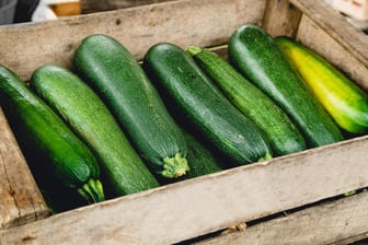 Zucchini in einer Holzkiste: Für eine reife Ernte sollten Sie Pflanzen an den richtigen Standort setzen und die Früchte zu einem bestimmten Zeitpunkt ernten.