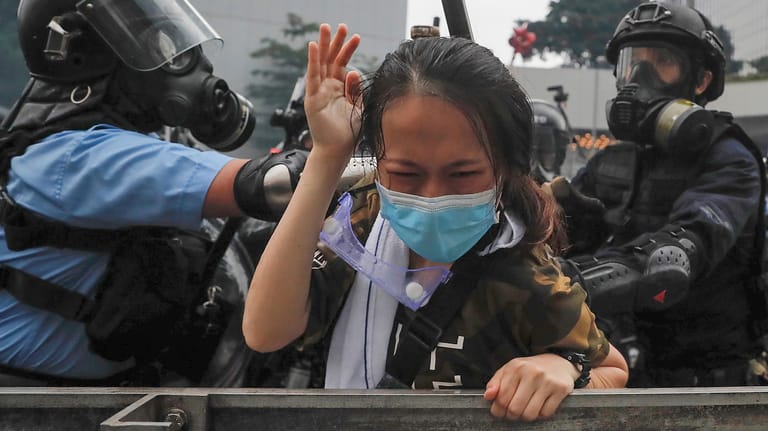 Polizisten drücken eine Demonstrantin gegen eine Absperrung. Bei neuen Protesten in Hongkong gegen das kontroverse Gesetz für Auslieferungen nach China ist es zu schweren Zusammenstößen mit der Polizei gekommen.