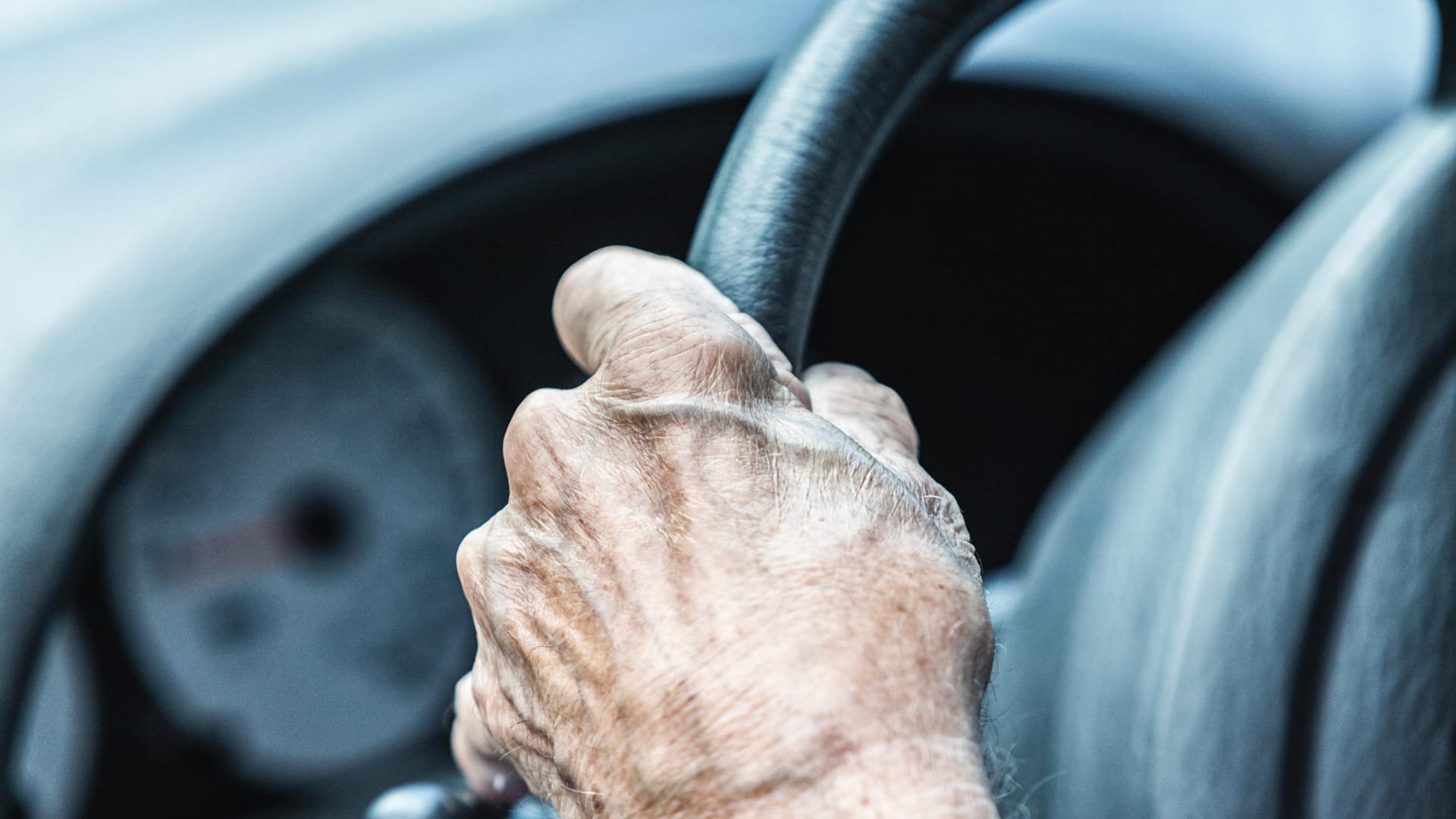 Elderly Senior Man Driver Hand Gripping Car Steering Wheel Close-Up