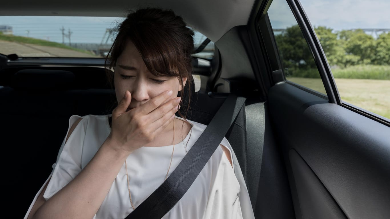 Einer jungen Frau wird im Auto schlecht: Reiseübelkeit kann einem in Bus, Bahn, Auto und Flugzeug widerfahren.