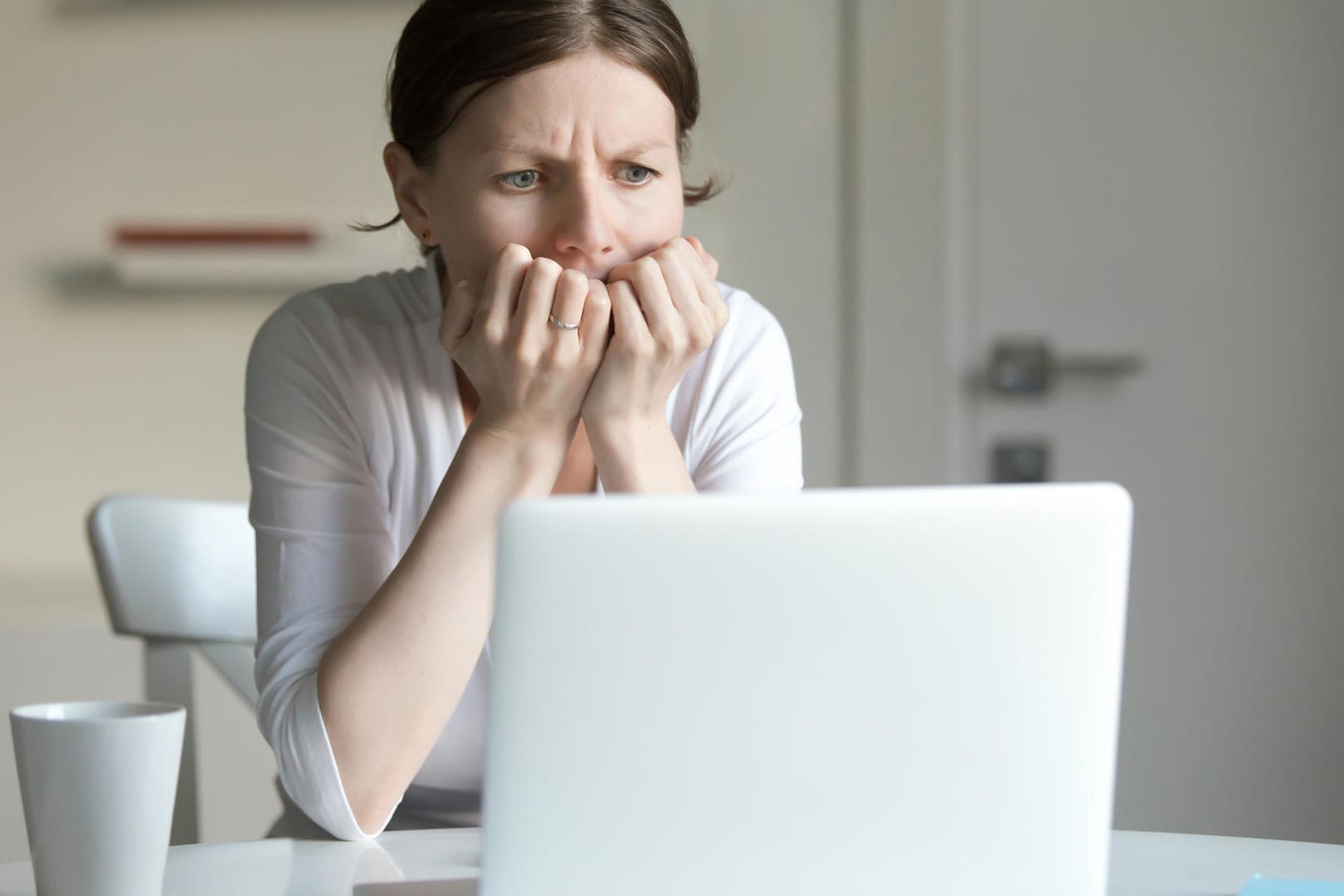 Eine Frau sitzt vor dem Notebook und hält sich die Hände vor den Mund: Auch Beleidigungen im Internet können den Betroffenen schwer zusetzen.