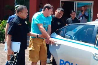 Wird in Chonburi von thailändischen Polizisten zu einem Polizeiauto geführt: Das von der Crime Suppression Division of Thailand zur Verfügung gestellte Foto zeigt Francesco Galdeli (Mi.) aus Italien, der sich jahrelang als George Clooney ausgegeben hat.