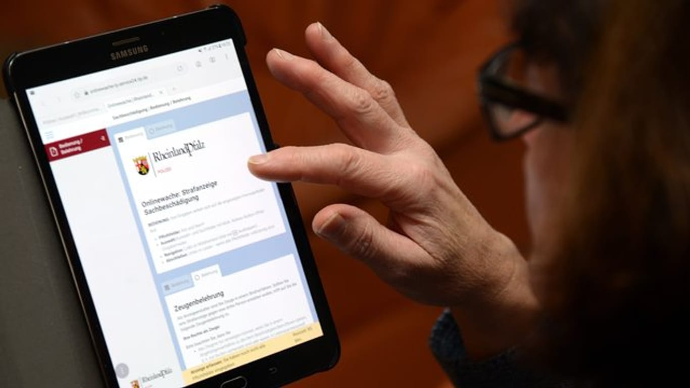 Eine Frau betrachtet die "Onlinewache" der Polizei von Rheinland-Pfalz auf einem Tablet: Die meisten online erstatteten Anzeigen erfolgten wegen Betrugs. (Symbolbild)