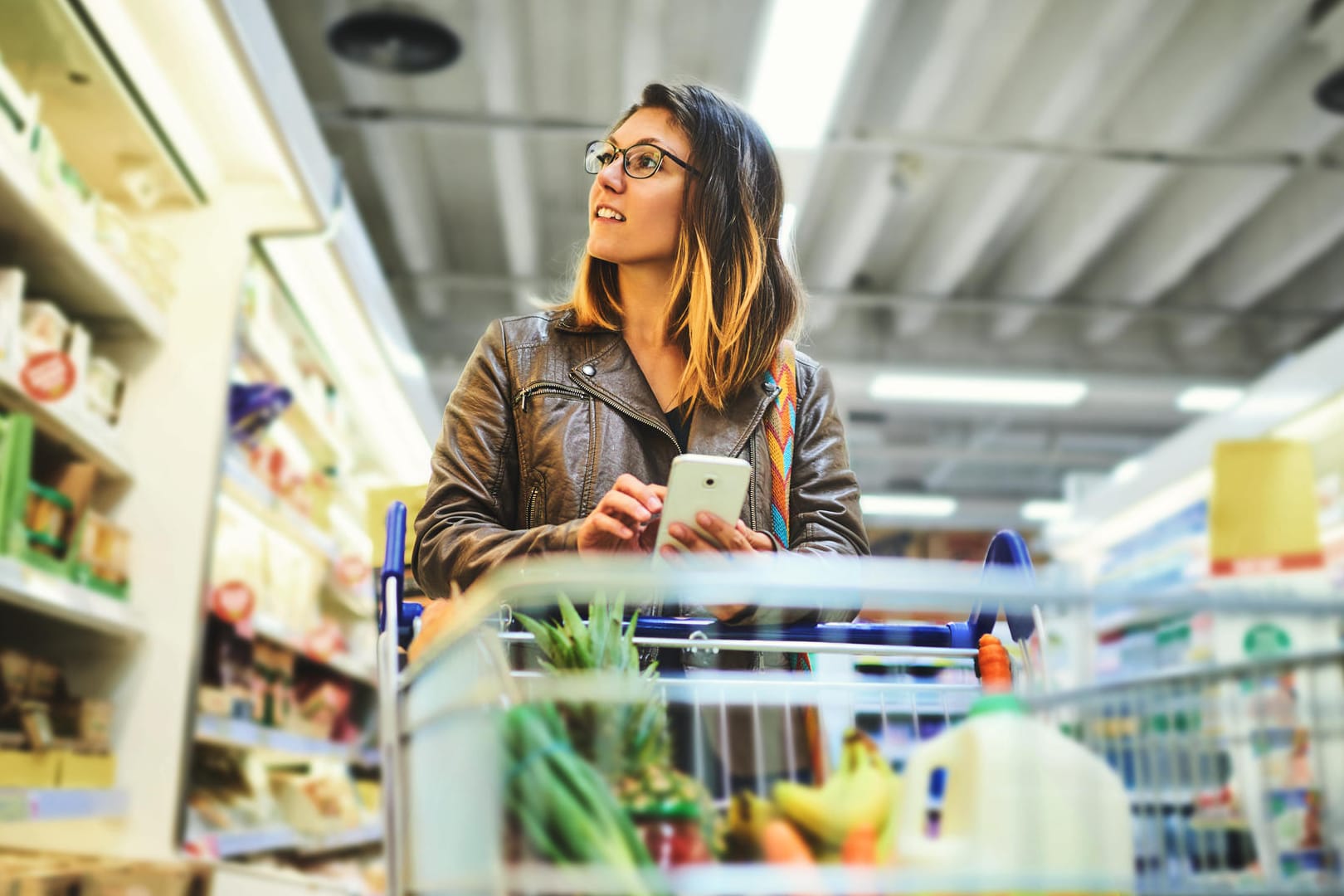 Eine Frau prüft mit ihrem Handy Lebensmittel: Die Ampel der App Grünzeit zeigt an, wann welches regionale Produkt Saison hat.