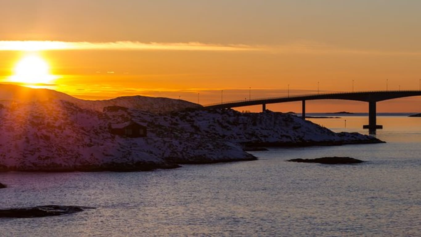 Die Sonne geht hinter der Sommaroy-Brücke unter, die die Inseln Kvaloya und Sommaroy verbindet.