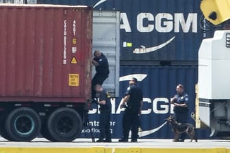 Mit einem Hund inspizieren Polizisten einen Container im Hafen von Philadelphia.