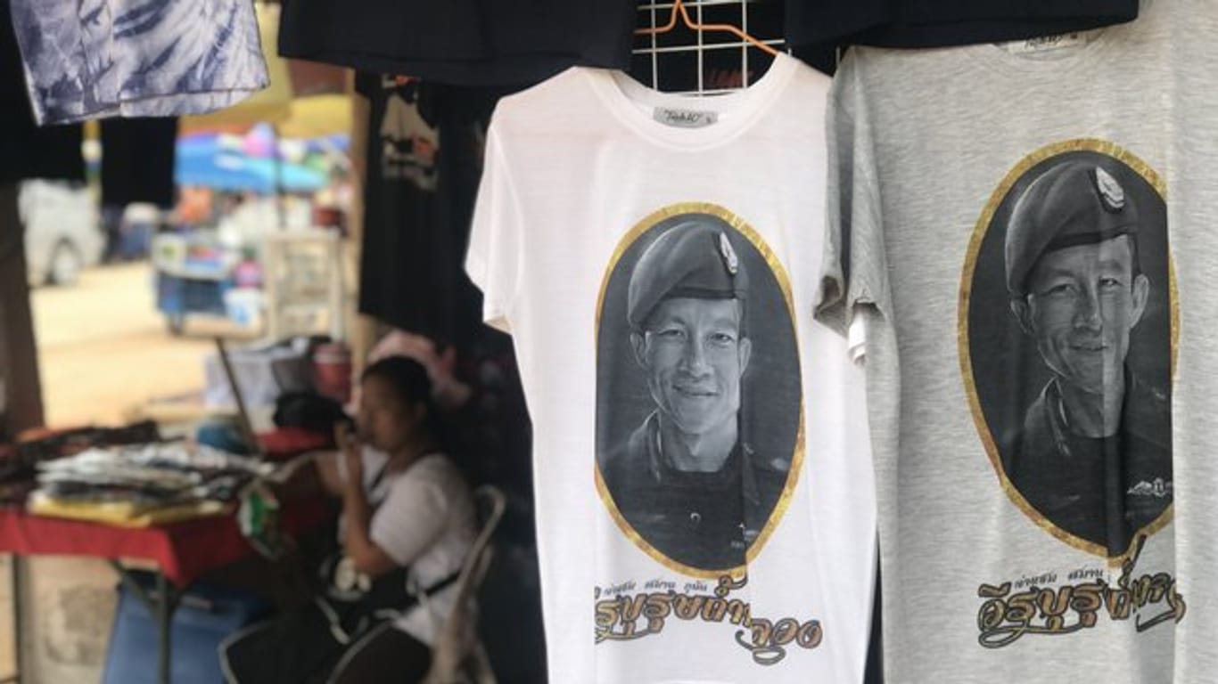 Vor der Tham-Luang-Höhle im äußersten Norden Thailands werden T-Shirts verkauft, auch mit dem Porträt des Ex-Marinetauchers Saman Kunan.