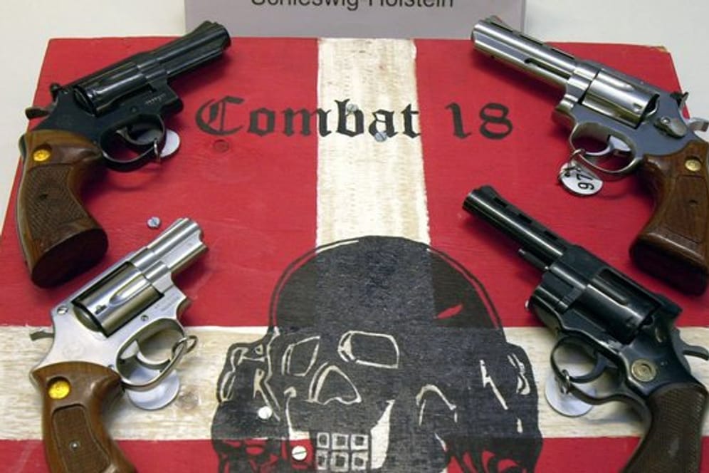Sichergestellte Waffen und ein Schild der Neonazi-Gruppierung "Combat 18" bei einer Pressekonferenz der Kieler Kripo.
