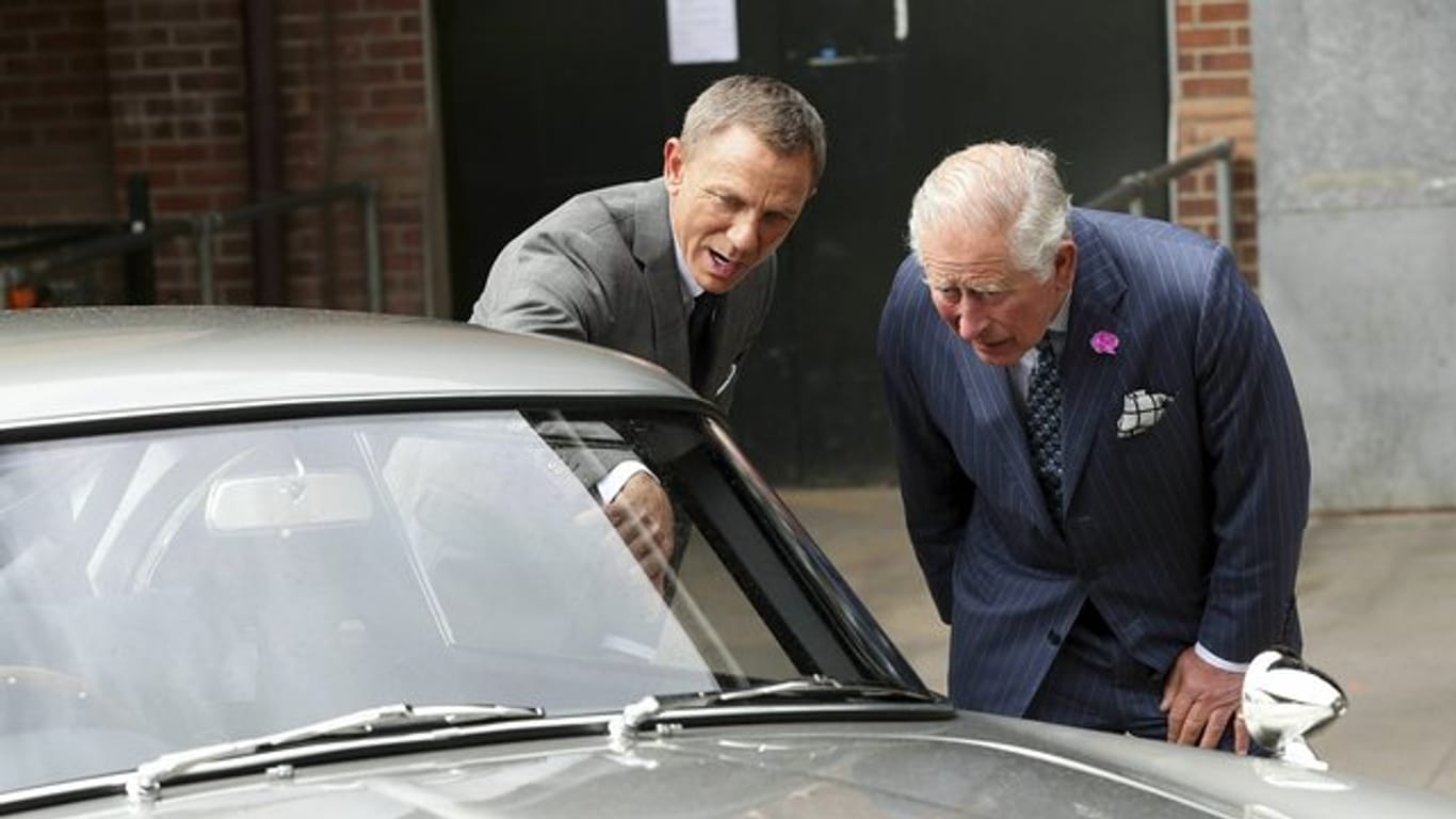 Daniel Craig (l) zeigt Prinz Charles (r) den Aston Martin DB5.