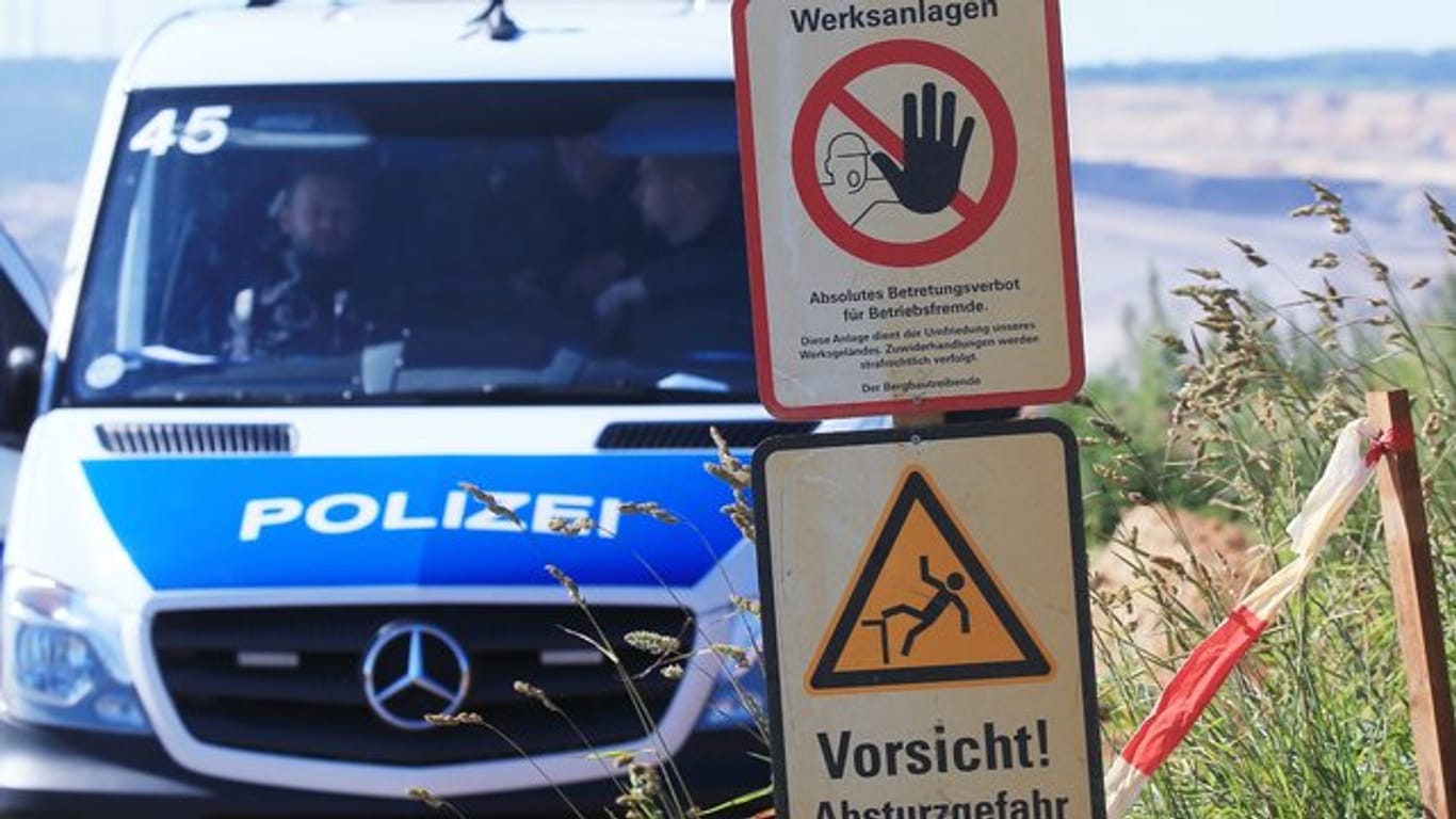 Polizeifahrzeug am Tagebau Garzweiler neben Warnschildern mit den Aufschriften "Werksanlagen".